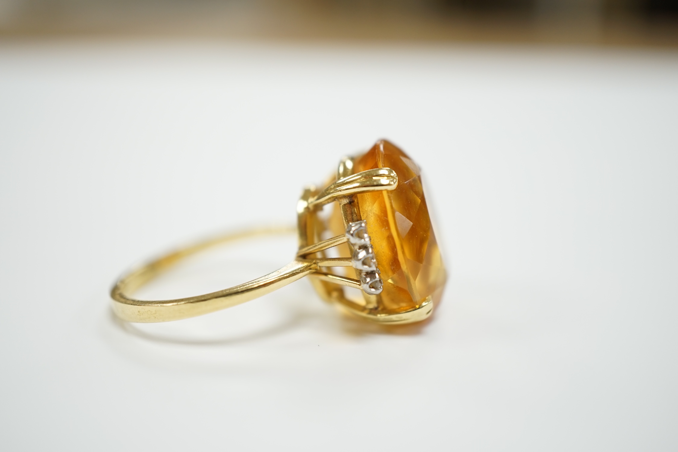 An 18k and single stone oval cut citrine set dress ring, with six stone diamond set shoulders, size R, gross weight 8.3 grams.